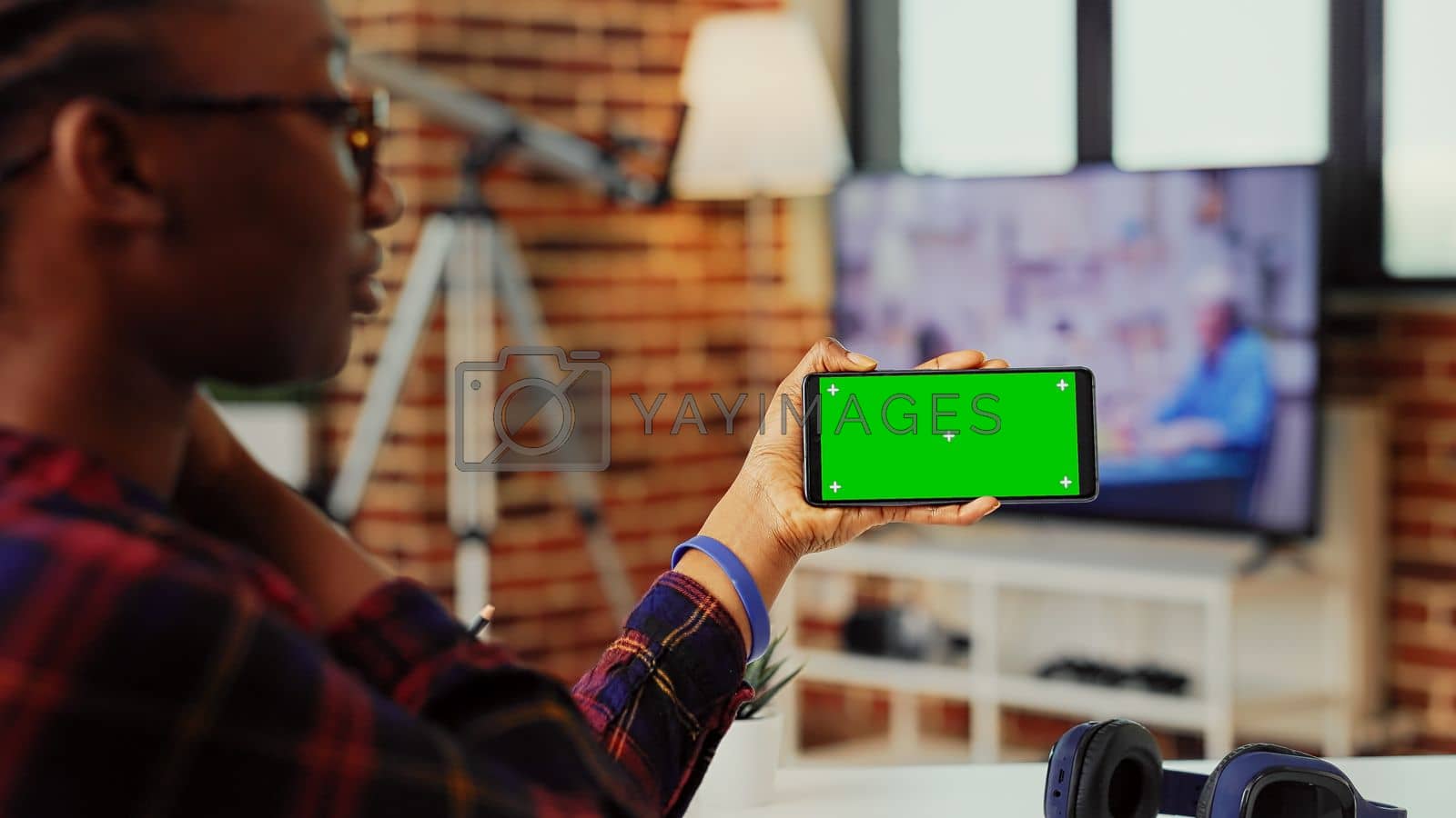 Royalty free image of Office employee holding smartphone with horizontal greenscreen by DCStudio