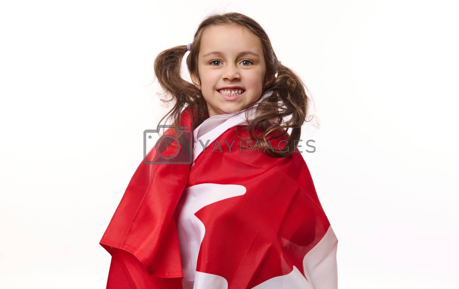Royalty free image of American lovely little girl wrapping Canada flag, smiling a beautiful toothy smile looking at camera, isolated on white by artgf