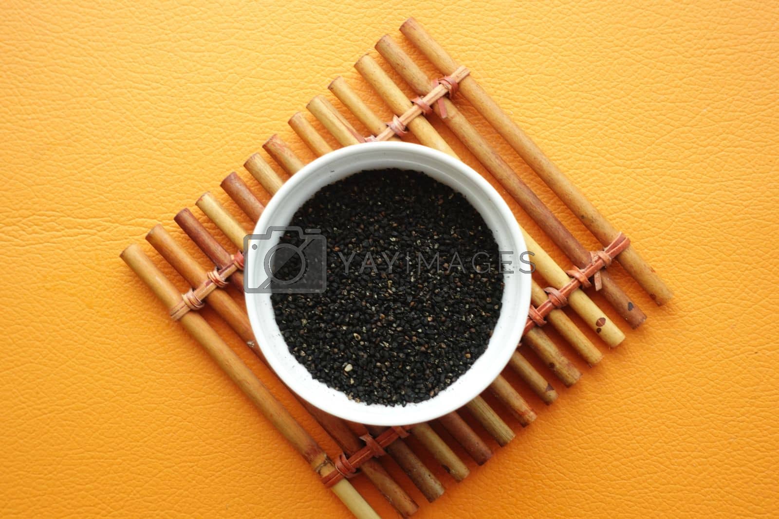 Royalty free image of Black Cumin in a container on orange background by towfiq007