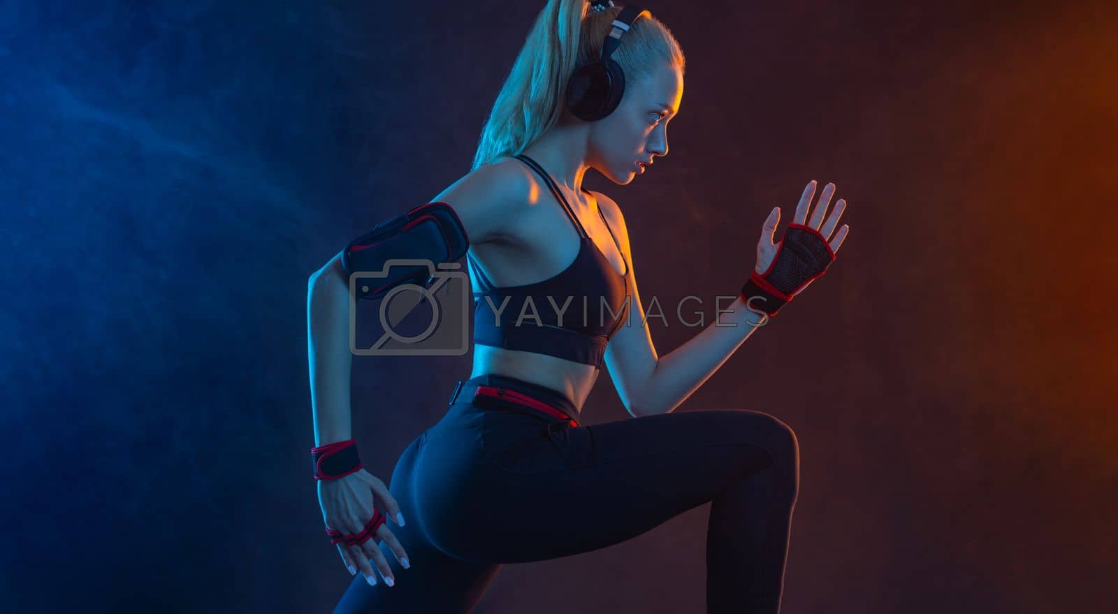 Royalty free image of Strong athletic fit woman on black with neon lights background wearing in the sportswear. Fitness and sport motivation. by MikeOrlov