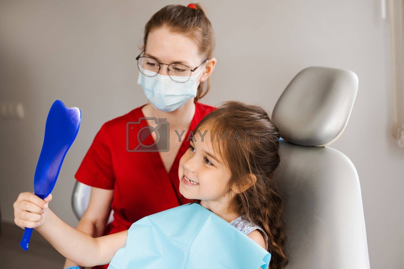Royalty free image of Children dentistry. Dentist and child patient. Consultation with child dentist at dentistry. Teeth treatment. Child looking in the mirror at the dentist. Happy child patient of dentistry. by Rabizo