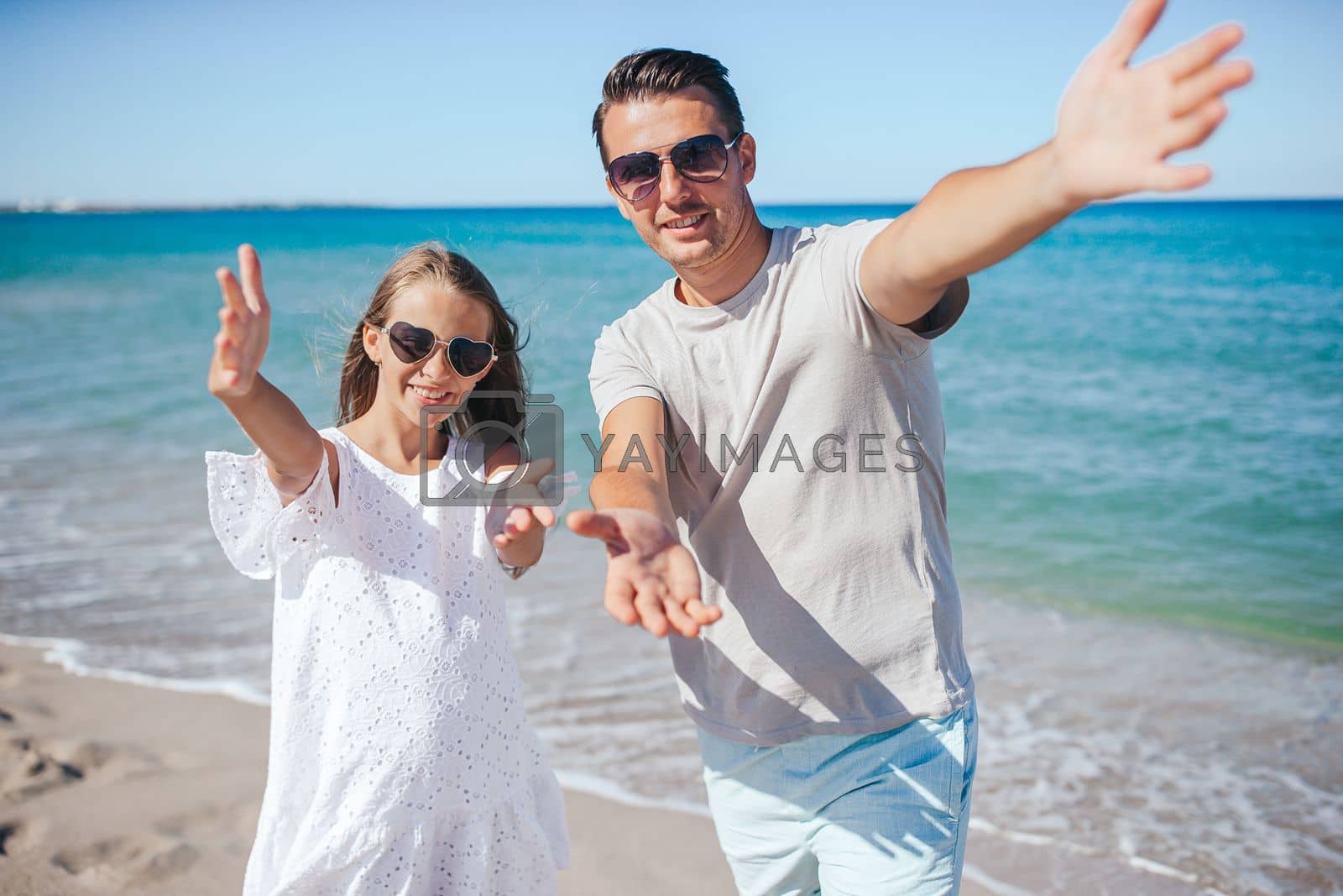 Royalty free image of Little girl and happy dad having fun during beach vacation by travnikovstudio