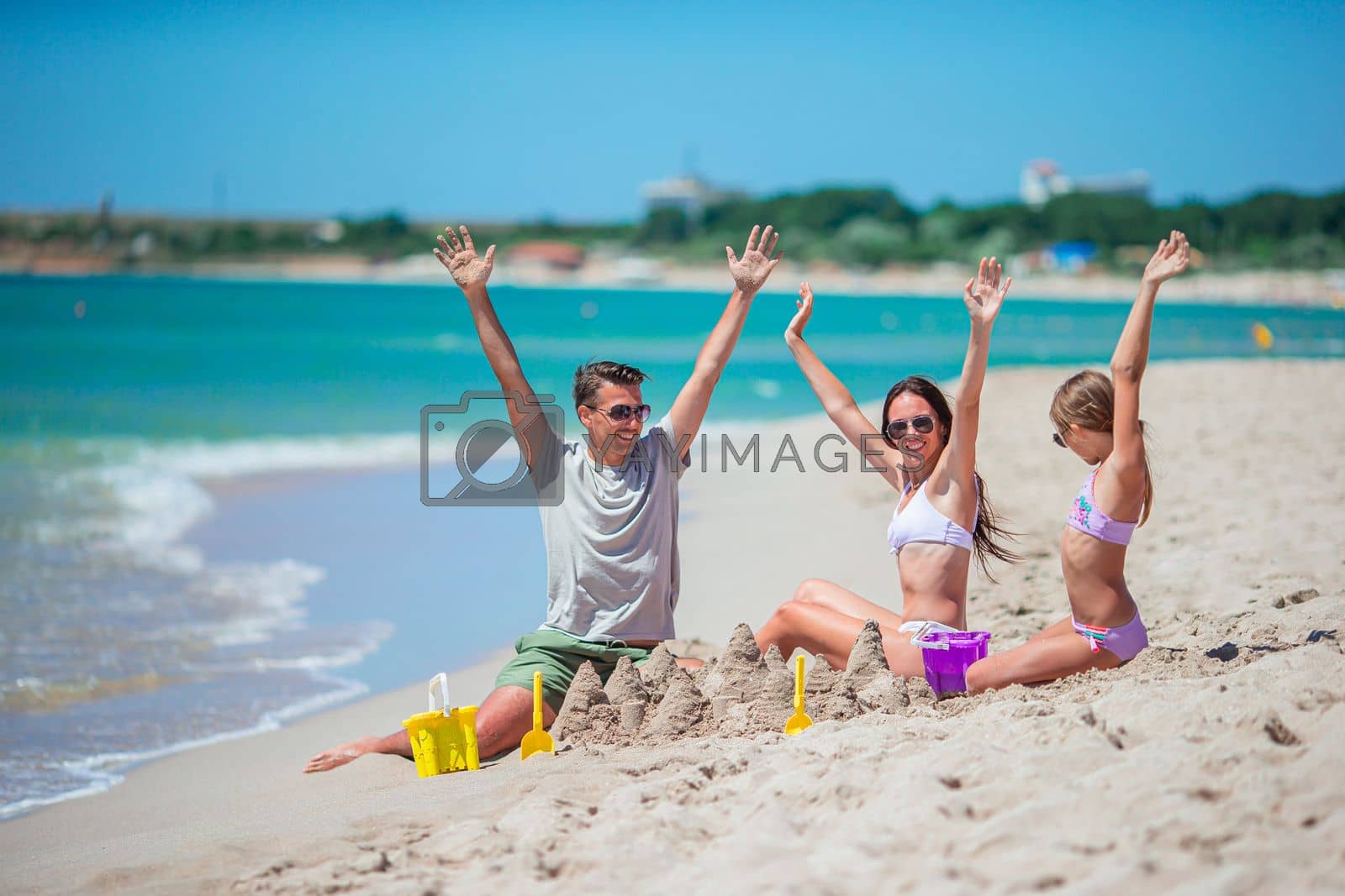Royalty free image of Family enjoying time on the beach making sand castle together on the seashore by travnikovstudio