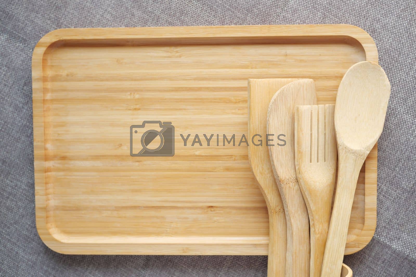 Royalty free image of wooden cutlery fork and spoon on a chopping board on table by towfiq007