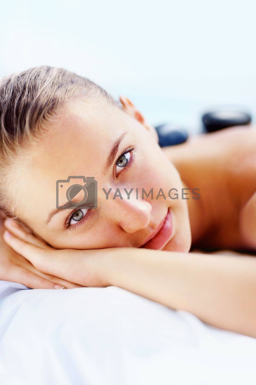 Royalty free image of Cute female in a spa with massage lastones on her back. Portrait of a cute young woman in a spa with massage lastones on her back. by YuriArcurs