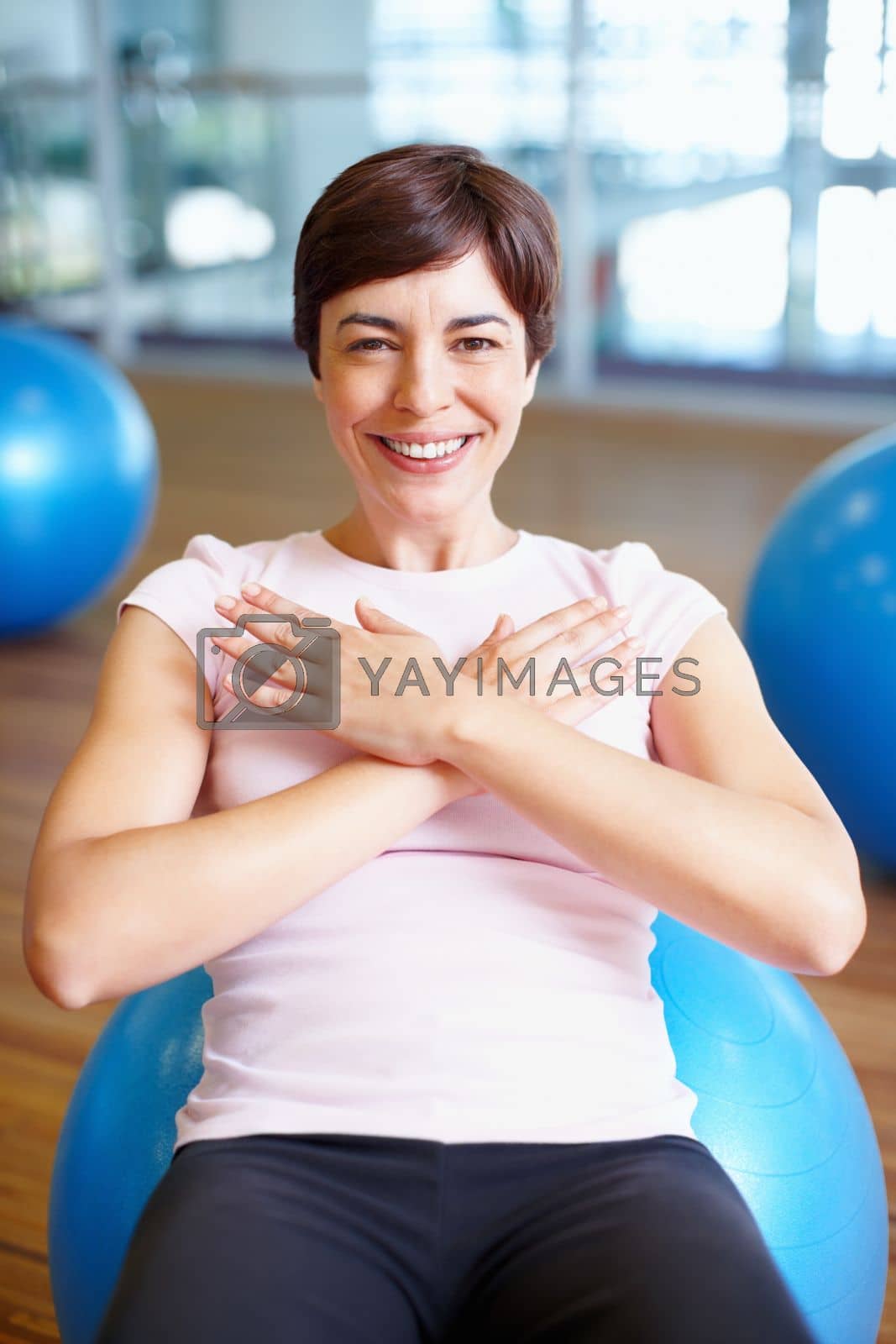 Royalty free image of Woman smiling during workout. Portrait of fit woman smiling while working out on pilates ball. by YuriArcurs
