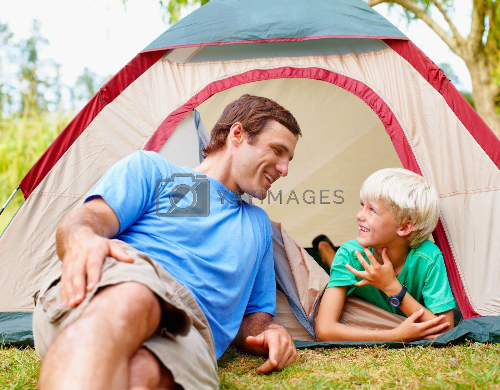 Royalty free image of Father and son relaxing in tent. Happy father and son relaxing in tent and looking at each other. by YuriArcurs