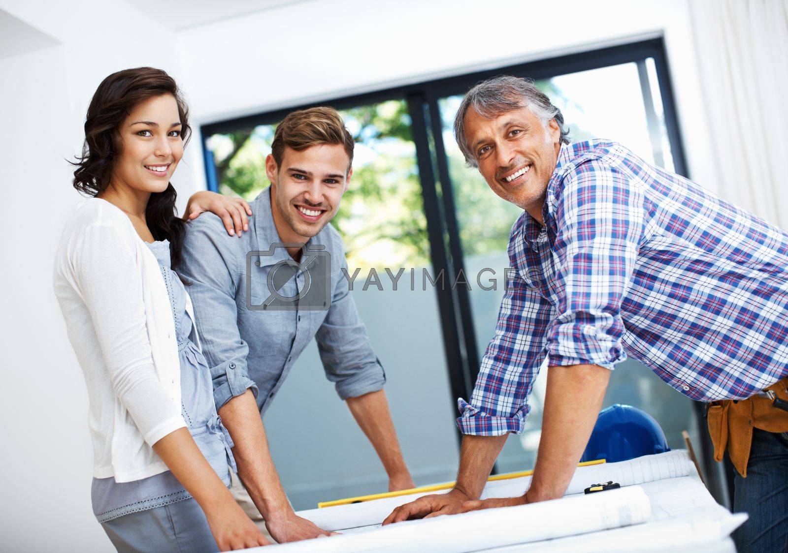 Royalty free image of Couple discussing with contractor in office. Portrait of mature contractor with attractive couple smiling in office. by YuriArcurs