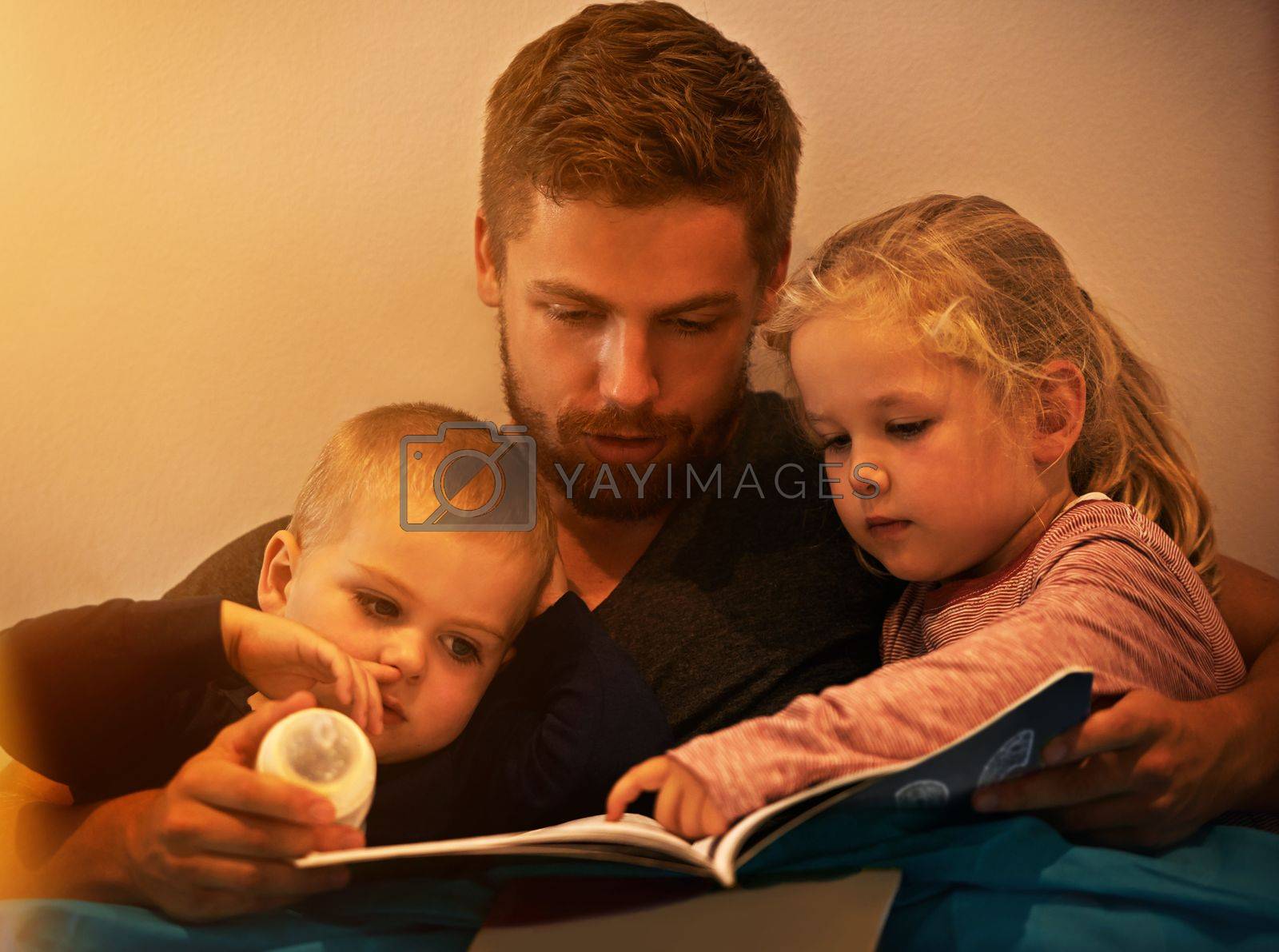 Royalty free image of They love the pictures. A father reading a bedtime story to his kids. by YuriArcurs