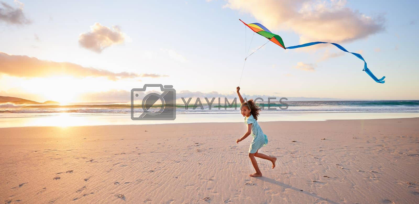 Royalty free image of Teach them well and let them lead the way. a little girl playing with her kite on the beach. by YuriArcurs