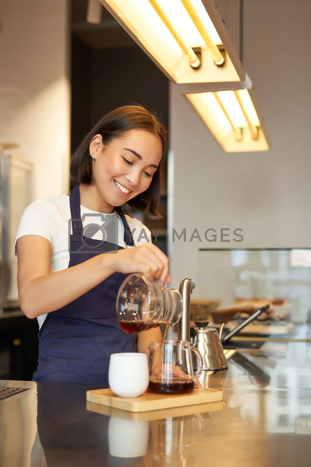 Royalty free image of Cute korean barista girl, pouring coffee, prepare filter batch brew pour over, working in cafe by Benzoix