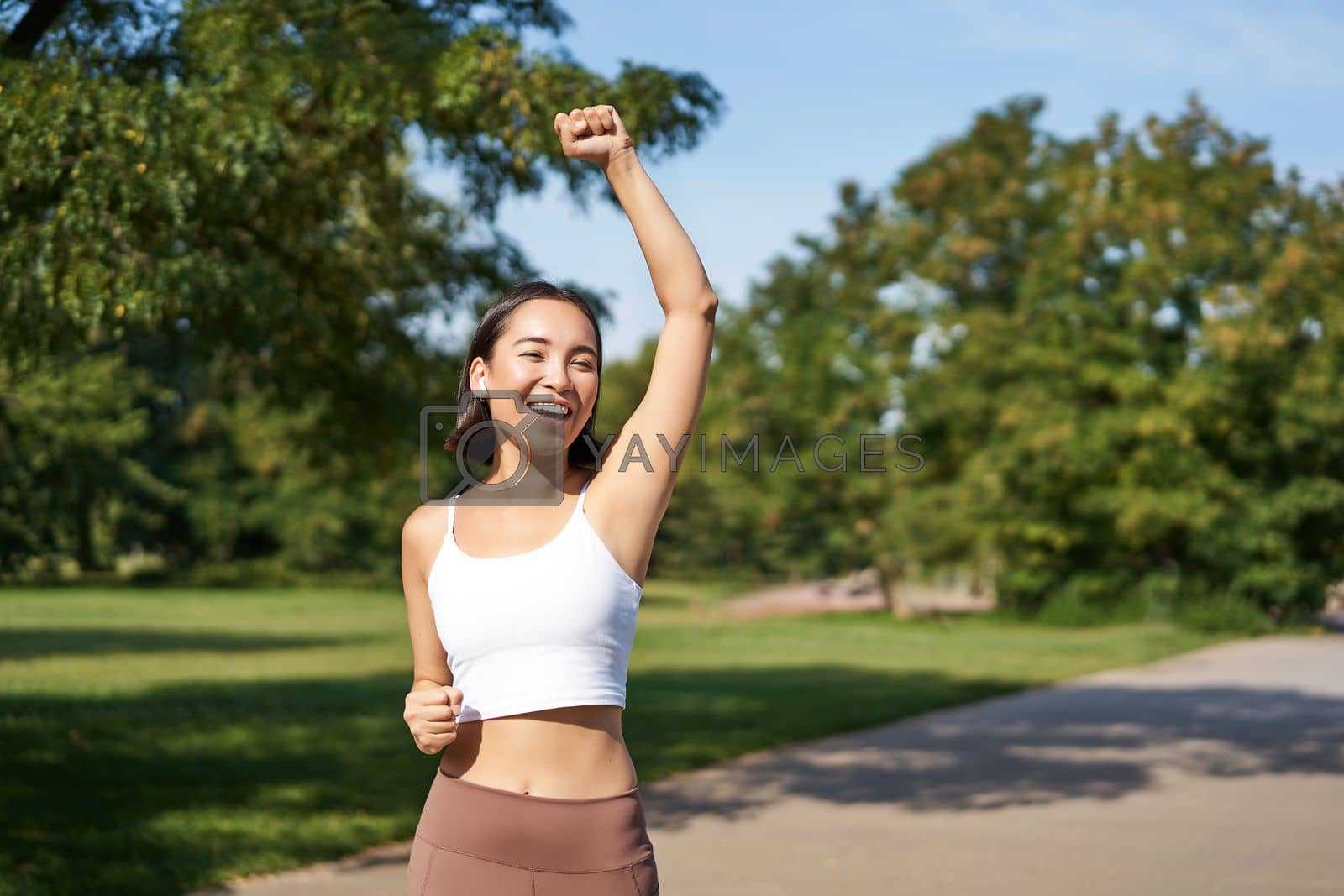 Royalty free image of Hooray, victory. Smiling asian girl triumphing, celebrating achievement, running till finish, shouting from excitement by Benzoix