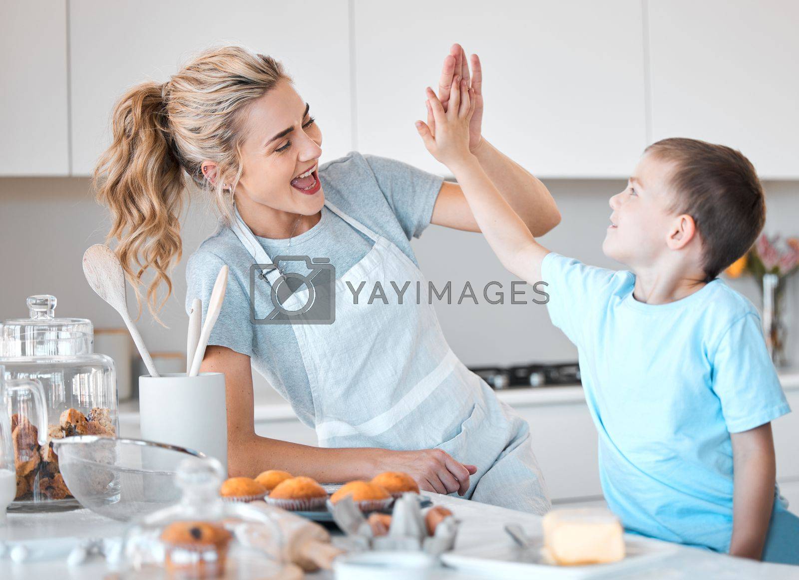 Royalty free image of Cheerful mother giving her son a high five. Happy mother and son baking together. Caucasian mother motivating her son while they bake together. Mother celebrating and baking with her son by YuriArcurs