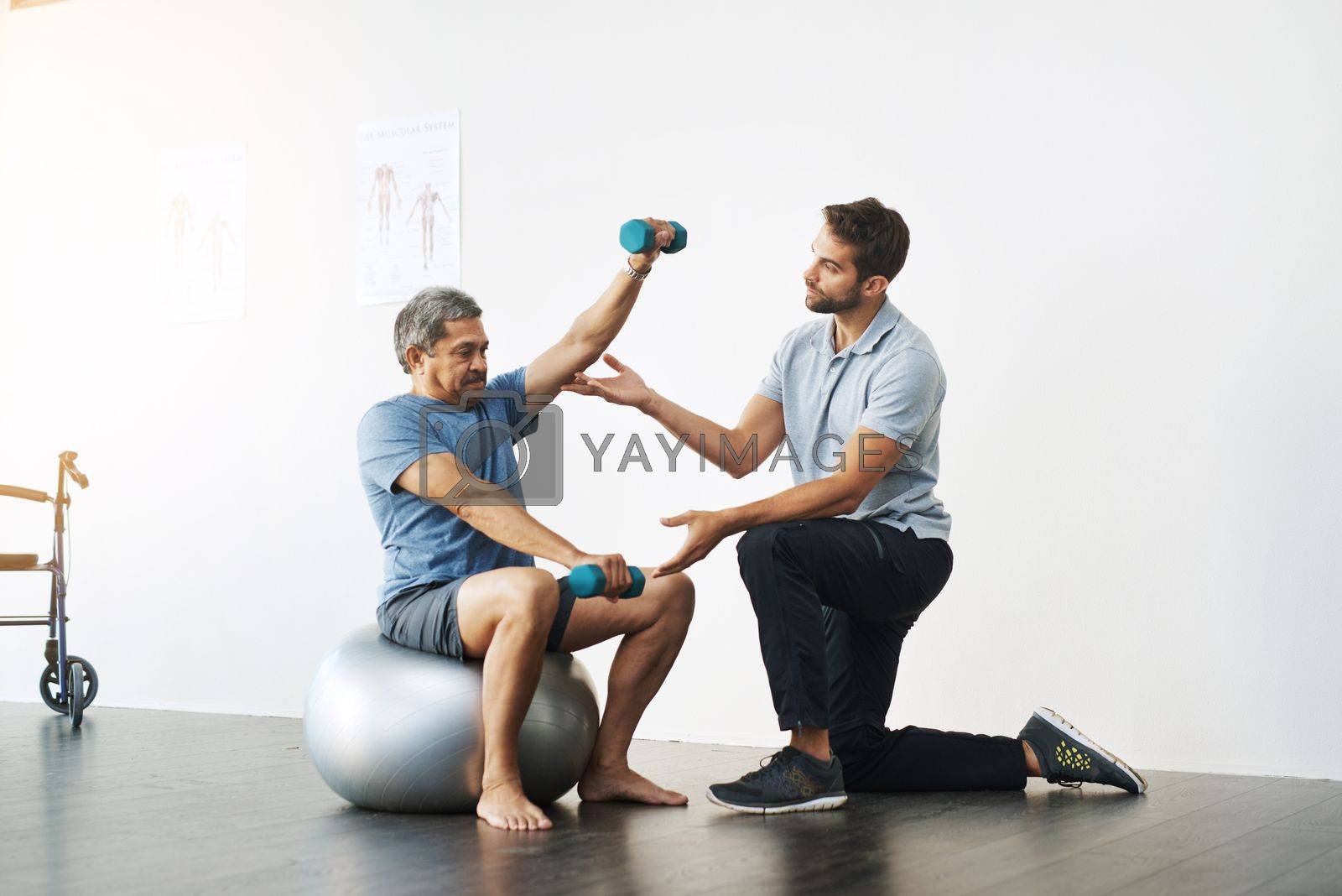 Royalty free image of Slow and easy movements. a young male physiotherapist helping a mature male patient with movement exercises at a clinic. by YuriArcurs