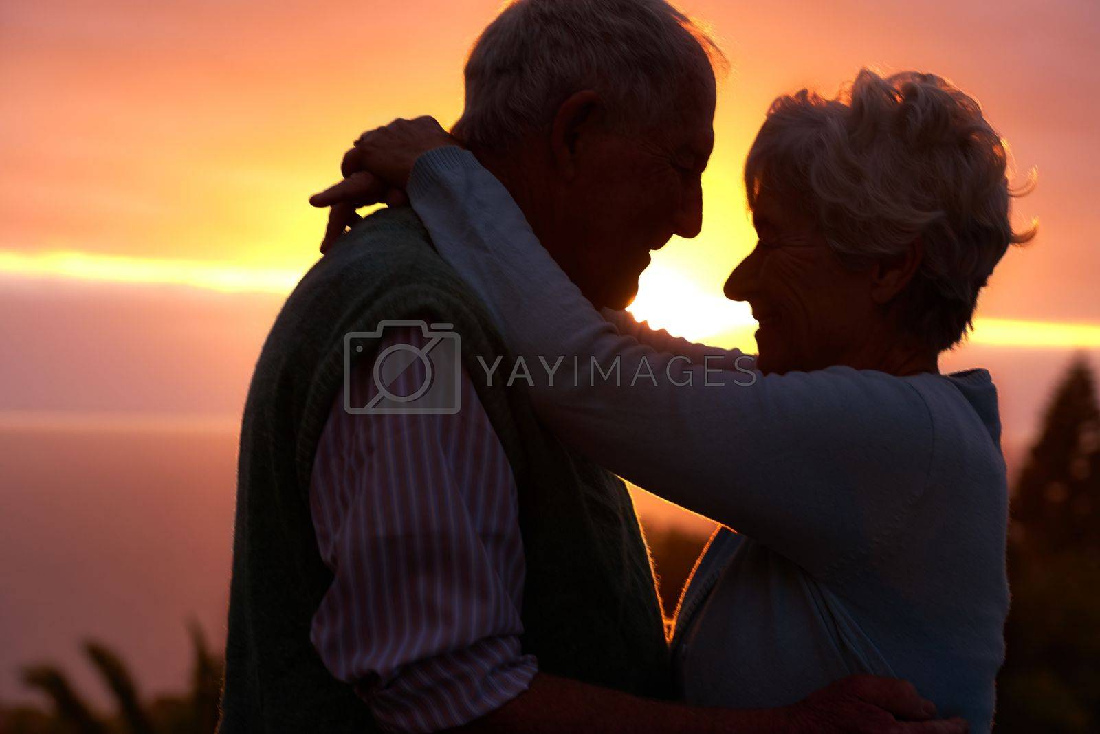 Royalty free image of The romance is still going strong. an elderly couple sharing a romantic moment at sunset. by YuriArcurs