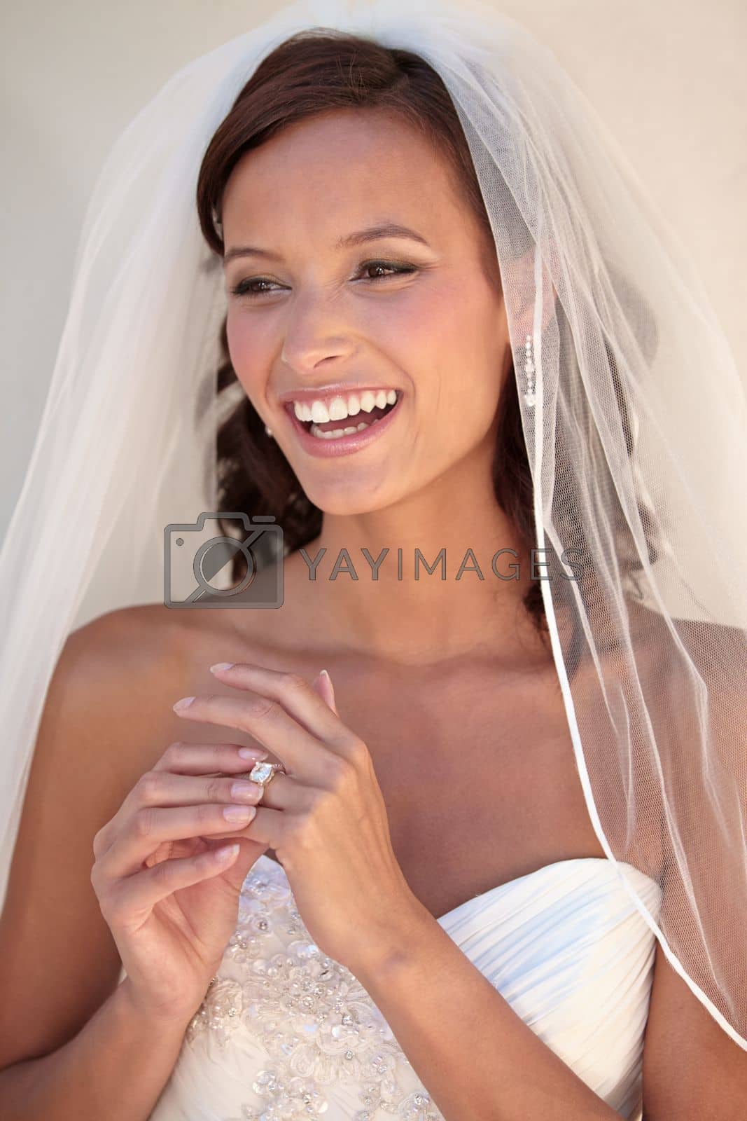 Royalty free image of Overjoyed to be newlywed. Beautiful bride in her wedding dress touching her wedding ring. by YuriArcurs