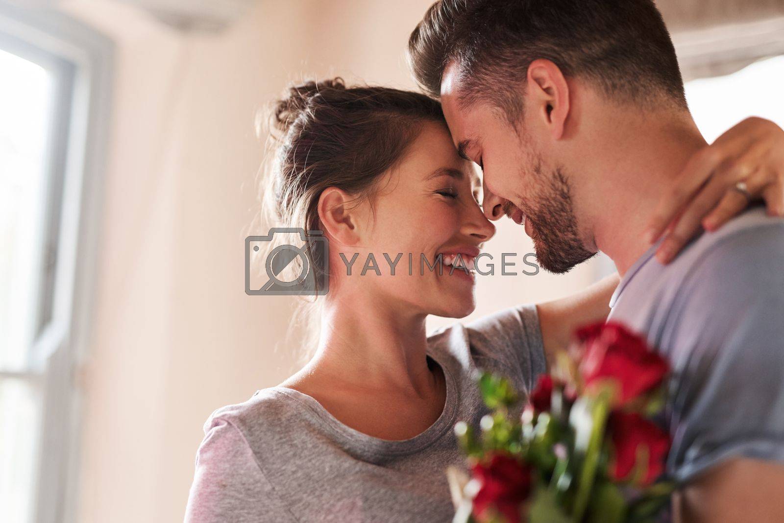 Royalty free image of Keep the romance alive in your relationship. a young man surprising his girlfriend with a bunch of roses in their bedroom at home. by YuriArcurs