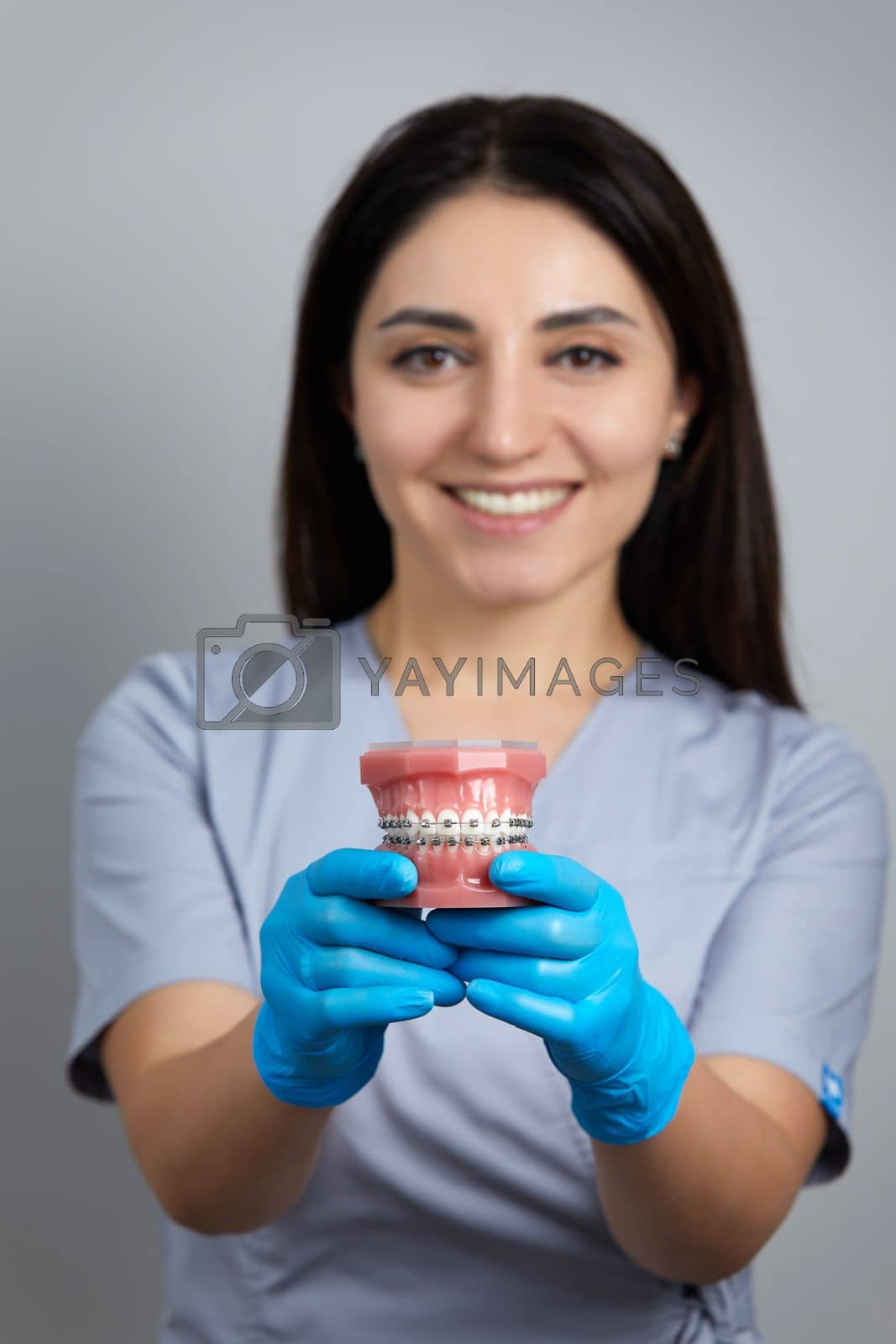 Royalty free image of Doctor orthodontist showing model of human jaw with wire braces attached by Mariakray