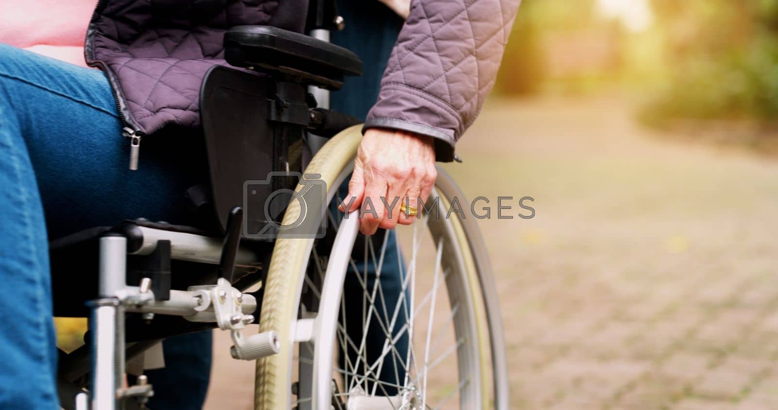 Royalty free image of The wheels keep on turning. an unrecognizable elderly woman in a wheelchair outside in a park during the day. by YuriArcurs