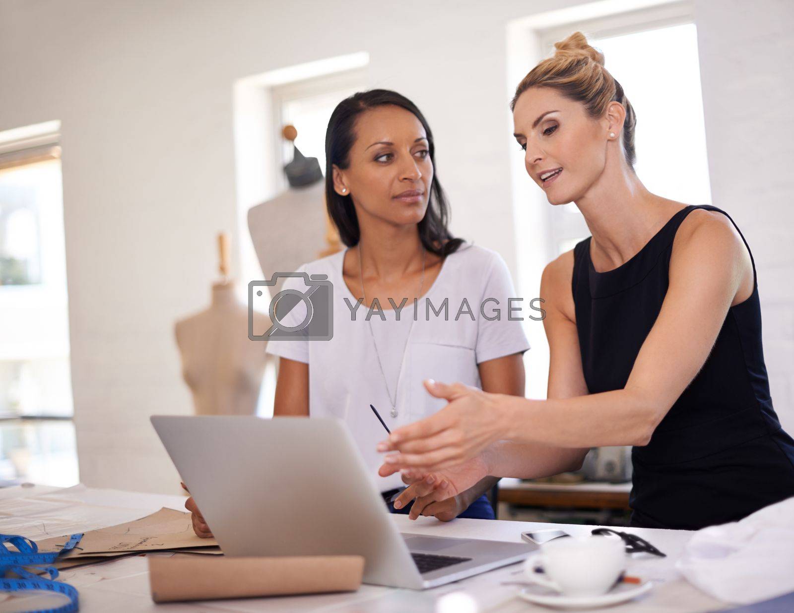 Royalty free image of Discussing the new fashion trends. Two young fashion designers discussing a design. by YuriArcurs