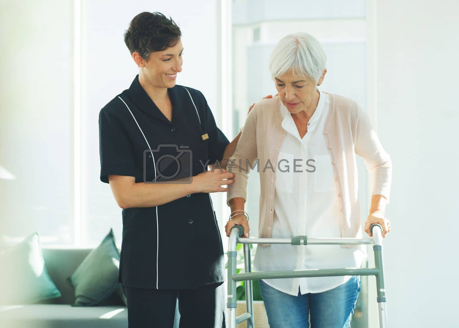 Royalty free image of Please help me. an attractive young healthcare professional helping her senior patient walk with a walker in a nursing home. by YuriArcurs