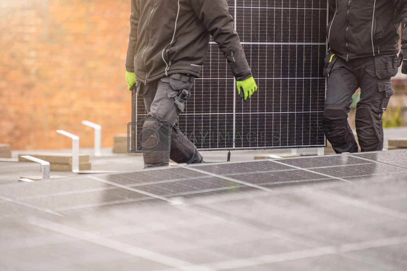 Royalty free image of The process of installing solar panels. Solar panel installers work on the roof. Installers carry solar panel module to installation site, green and renewable energy concept by SERSOL