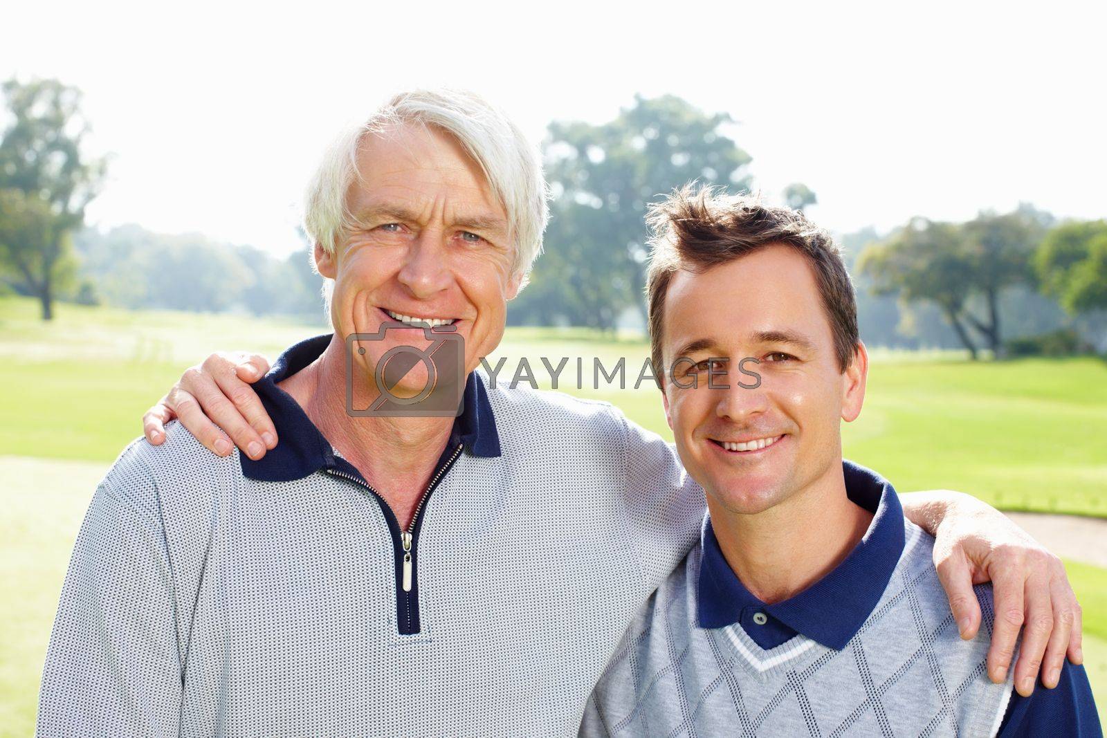 Royalty free image of Father and son on the golf course. Closeup of father and son standing on golf course with arms around and smiling. by YuriArcurs
