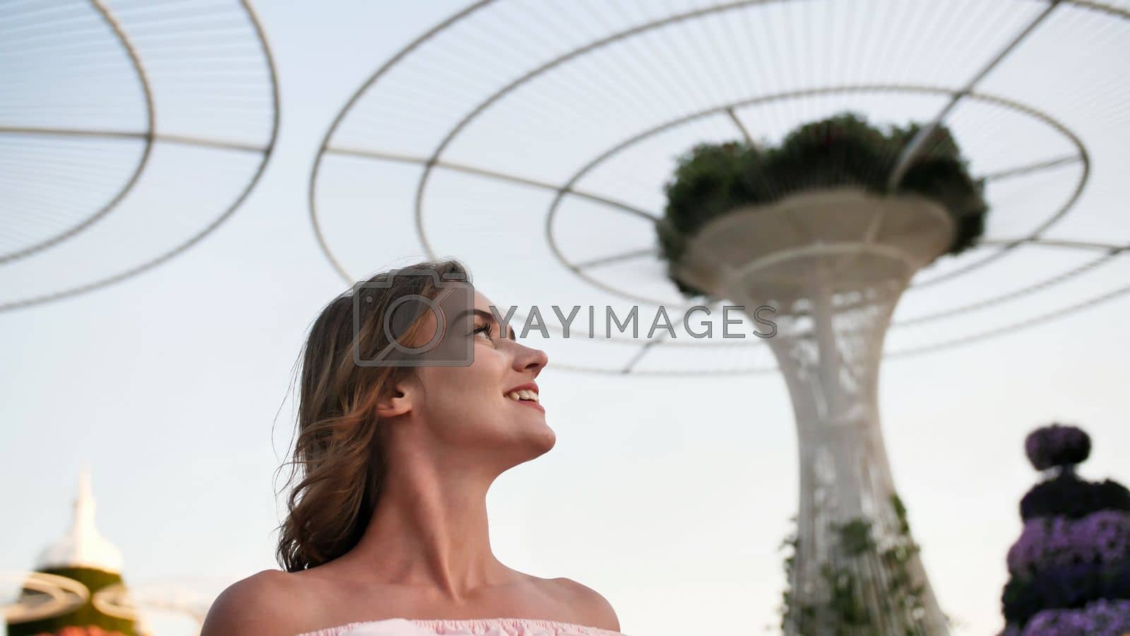 Royalty free image of Girl on the background futuristic metal flowers in Dubai Miracle Garden Park. by DovidPro
