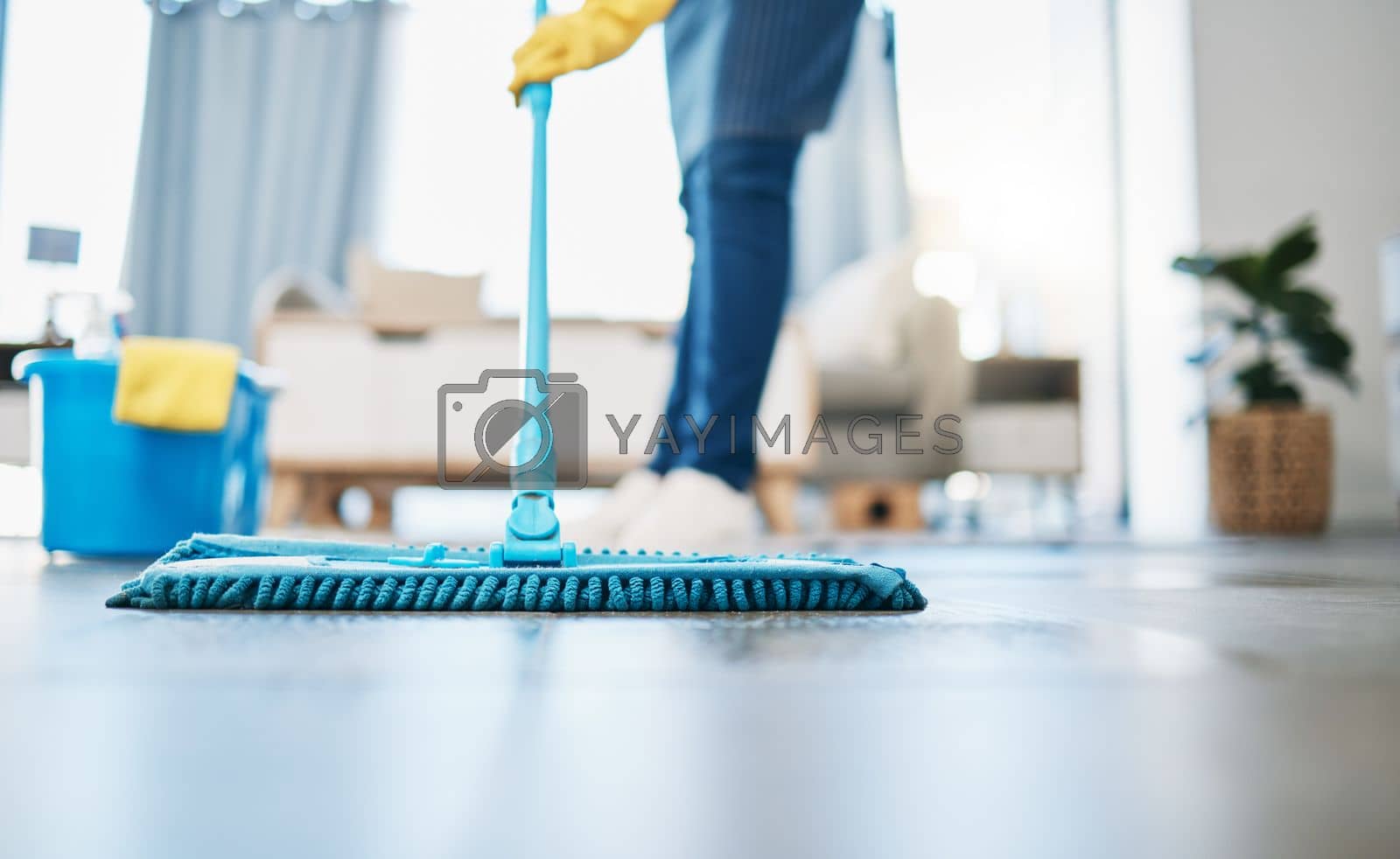 Royalty free image of Housekeeping, cleaning and woman maid with a mop to clean the living room floor at a house. Female domestic worker, cleaner and housewife washing the ground for bacteria, dust or dirt in her home. by YuriArcurs