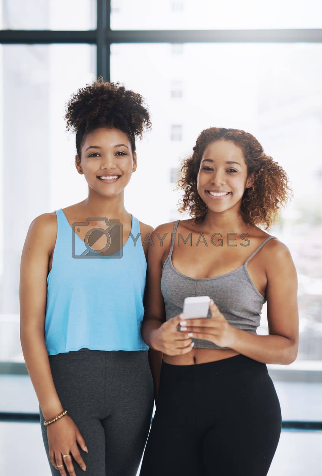 Royalty free image of Yoga keeps us smiling. Cropped portrait of two young women looking at a cellphone after yoga class. by YuriArcurs