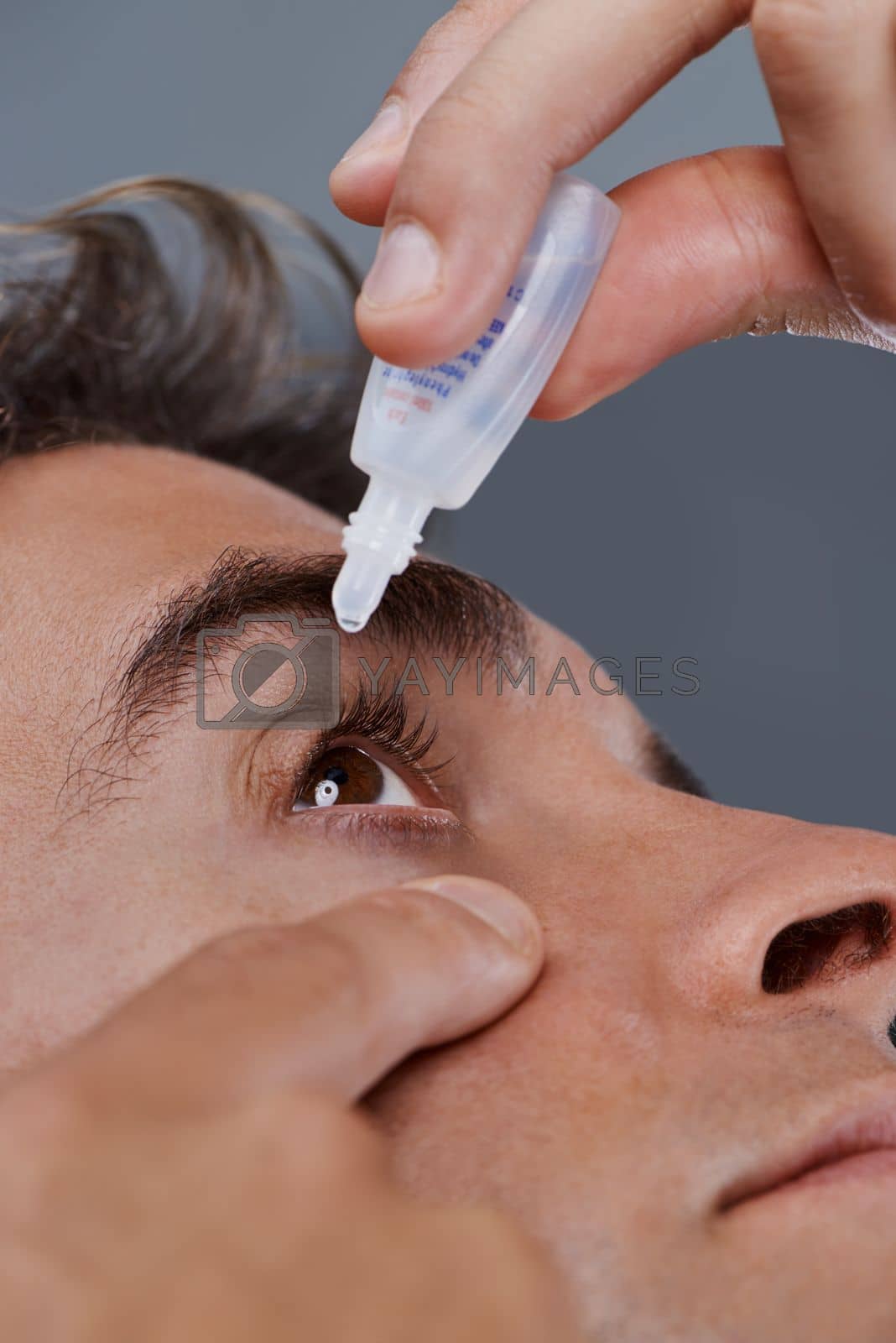 Royalty free image of Keeping his eyes clear. Studio shot of a young man putting drops into his eye. by YuriArcurs