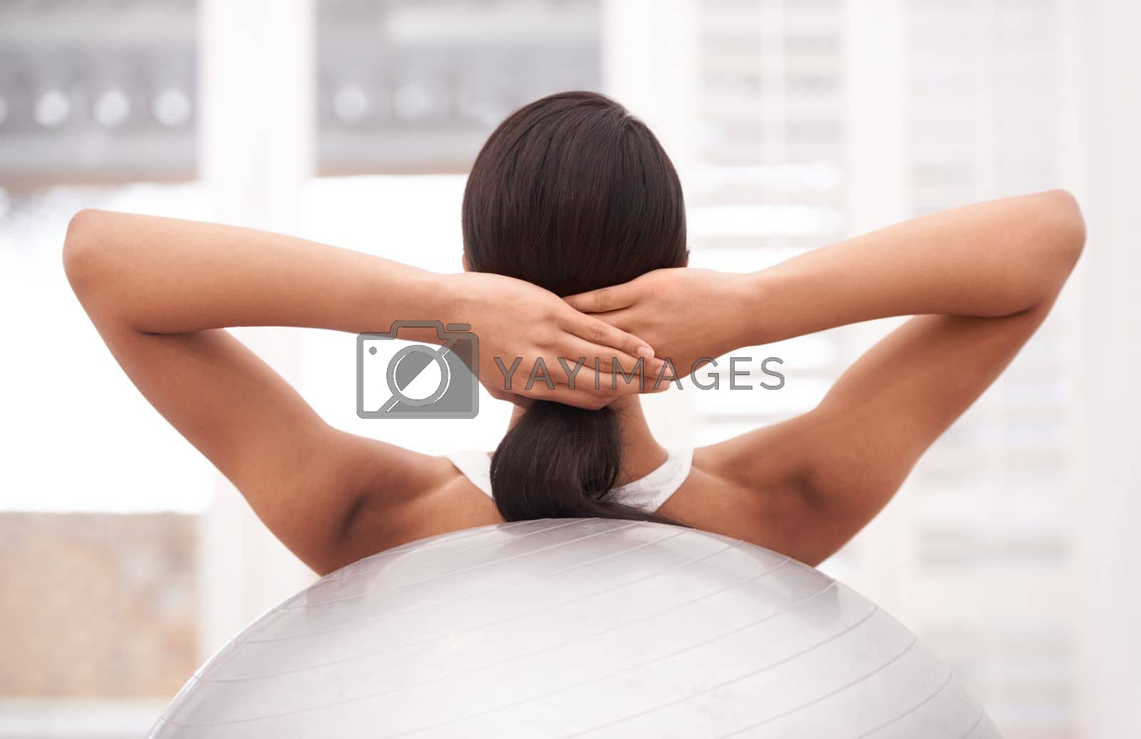 Royalty free image of Using the ball to strengthen the core. A young woman doing sit-ups using a pilates ball. by YuriArcurs