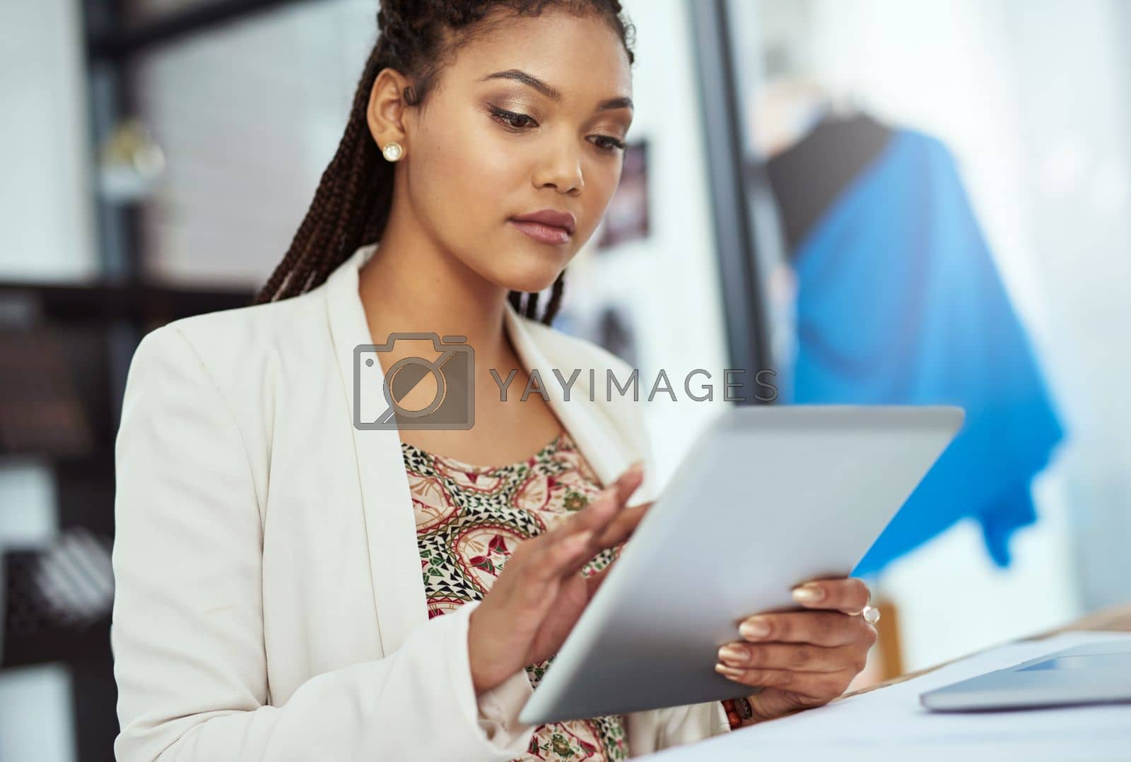 Royalty free image of Shes a modern day fashion designer. a young fashion designer working on her tablet. by YuriArcurs