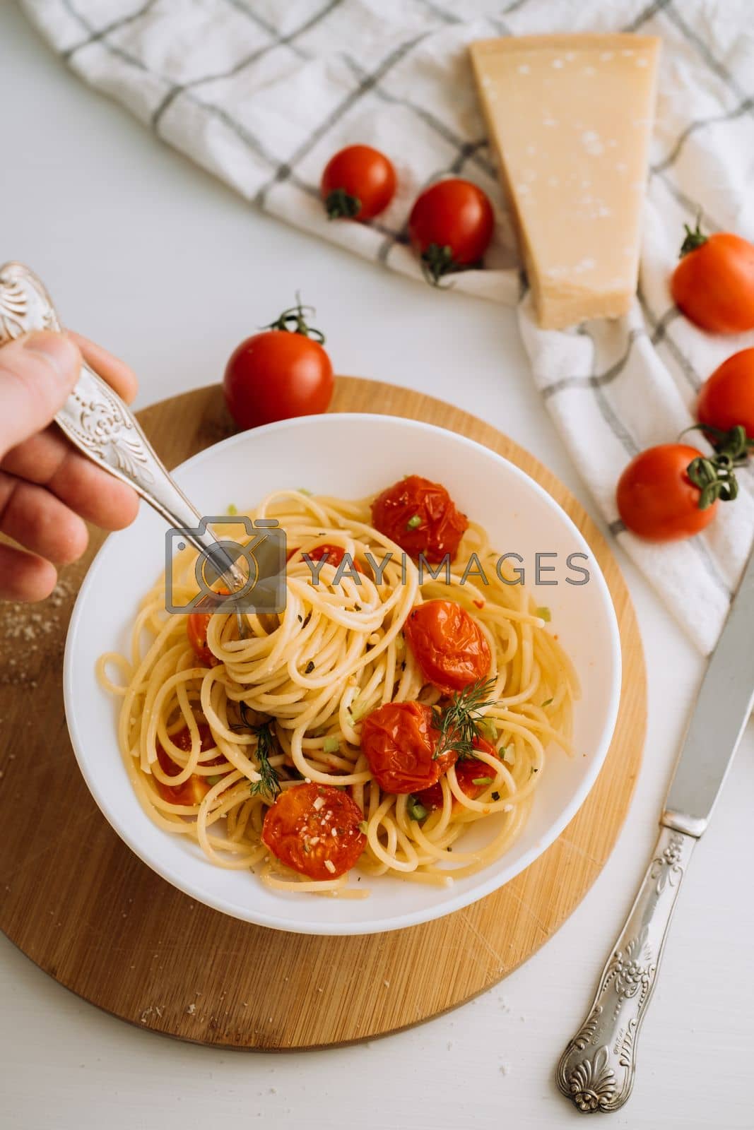 Royalty free image of Portion of spaghetti pasta with parmesan and cherry tomatoes sprinkled with spices in a plate on a wooden board by Romvy