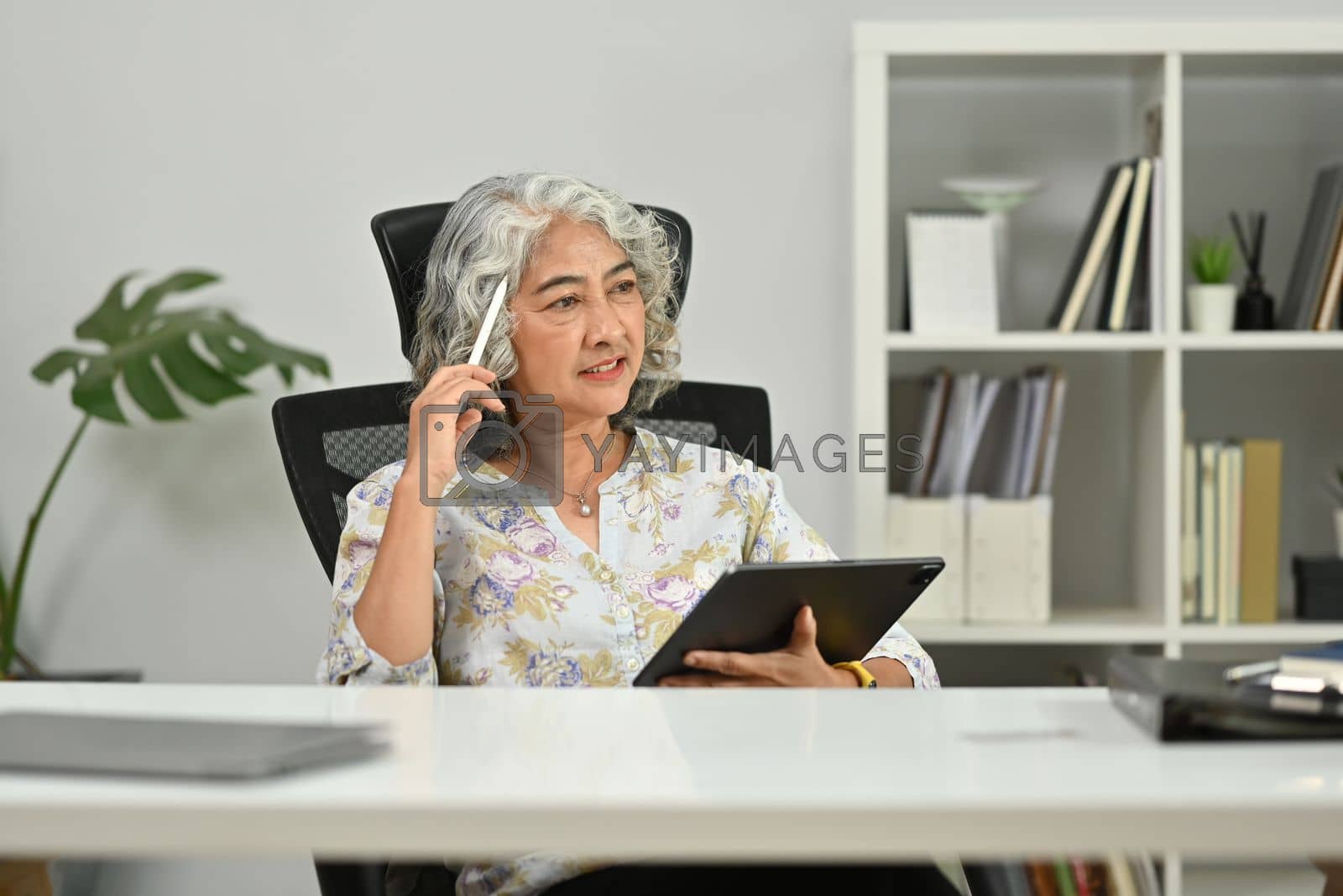Royalty free image of Thoughtful middle aged woman, daydreaming and looking away. Retirement, technology concept by prathanchorruangsak