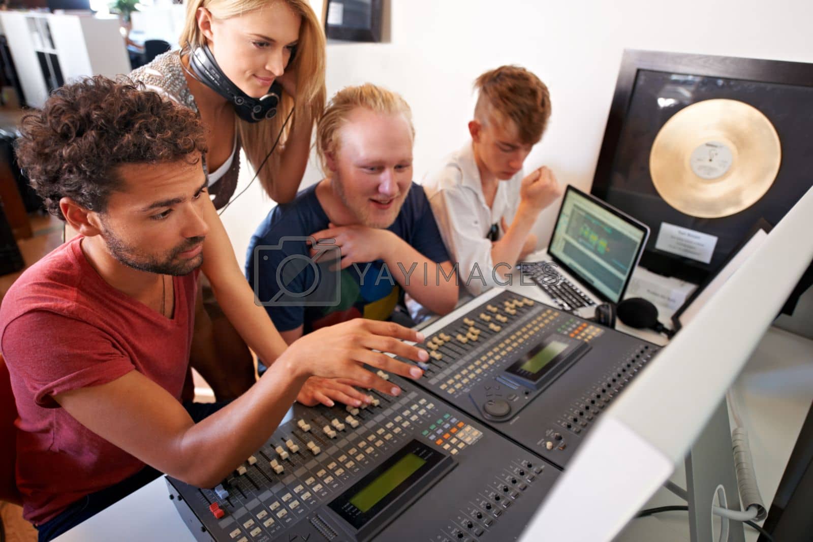 Royalty free image of This song just needs some tweaking...Four young music producers working on a mixing desk. by YuriArcurs
