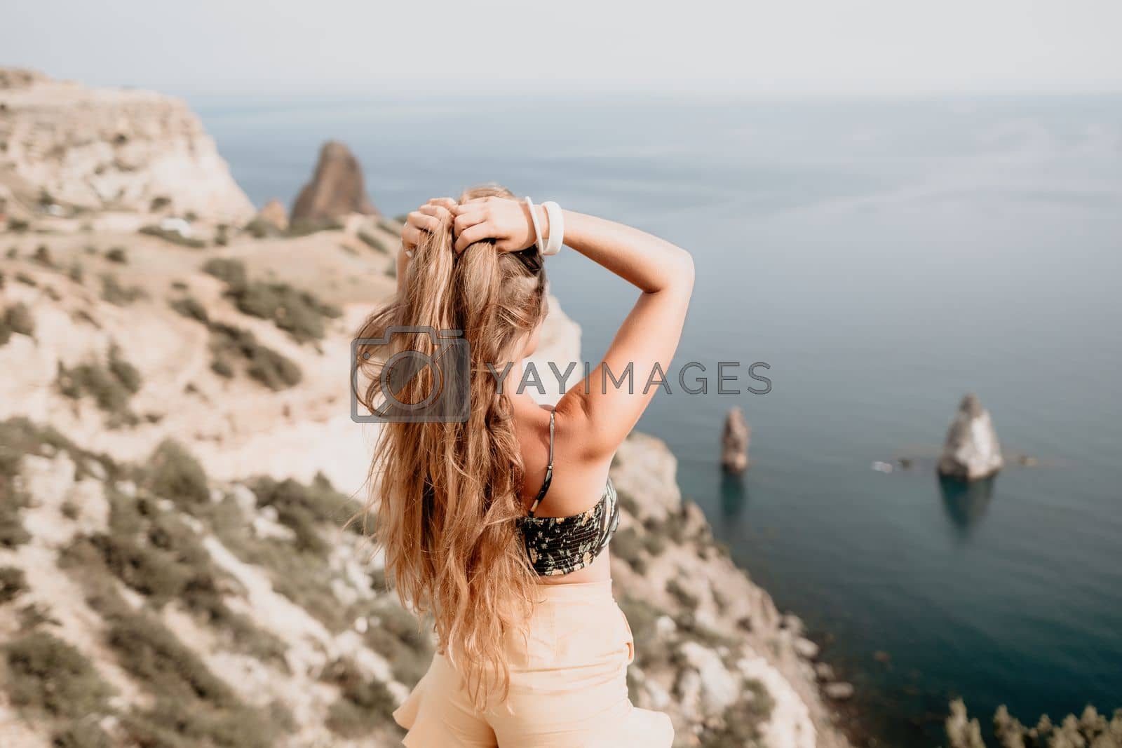Royalty free image of Woman travel sea. Happy tourist taking picture outdoors for memories. Woman traveler looks at the edge of the cliff on the sea bay of mountains, sharing travel adventure journey by panophotograph