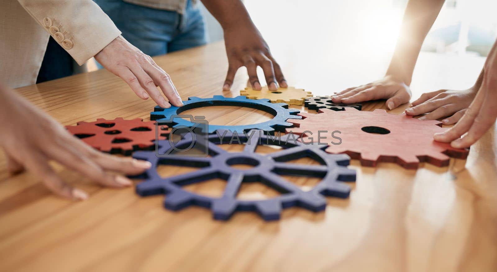 Royalty free image of Hands, collaboration and gear with a business team working together in synergy for innovation at a workshop. Meeting, teamwork and creative with a man and woman employee group at work in the office by YuriArcurs