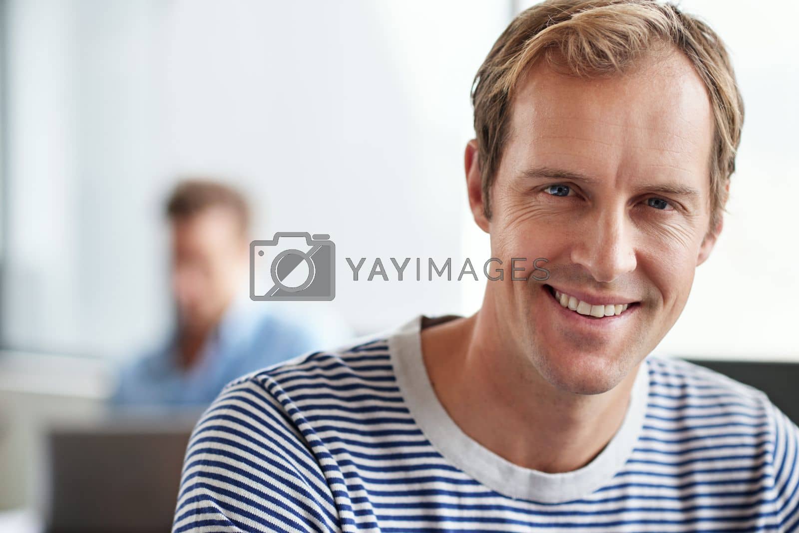 Royalty free image of Workplace contentment. Portrait of smiling man sitting in a casual work environment. by YuriArcurs