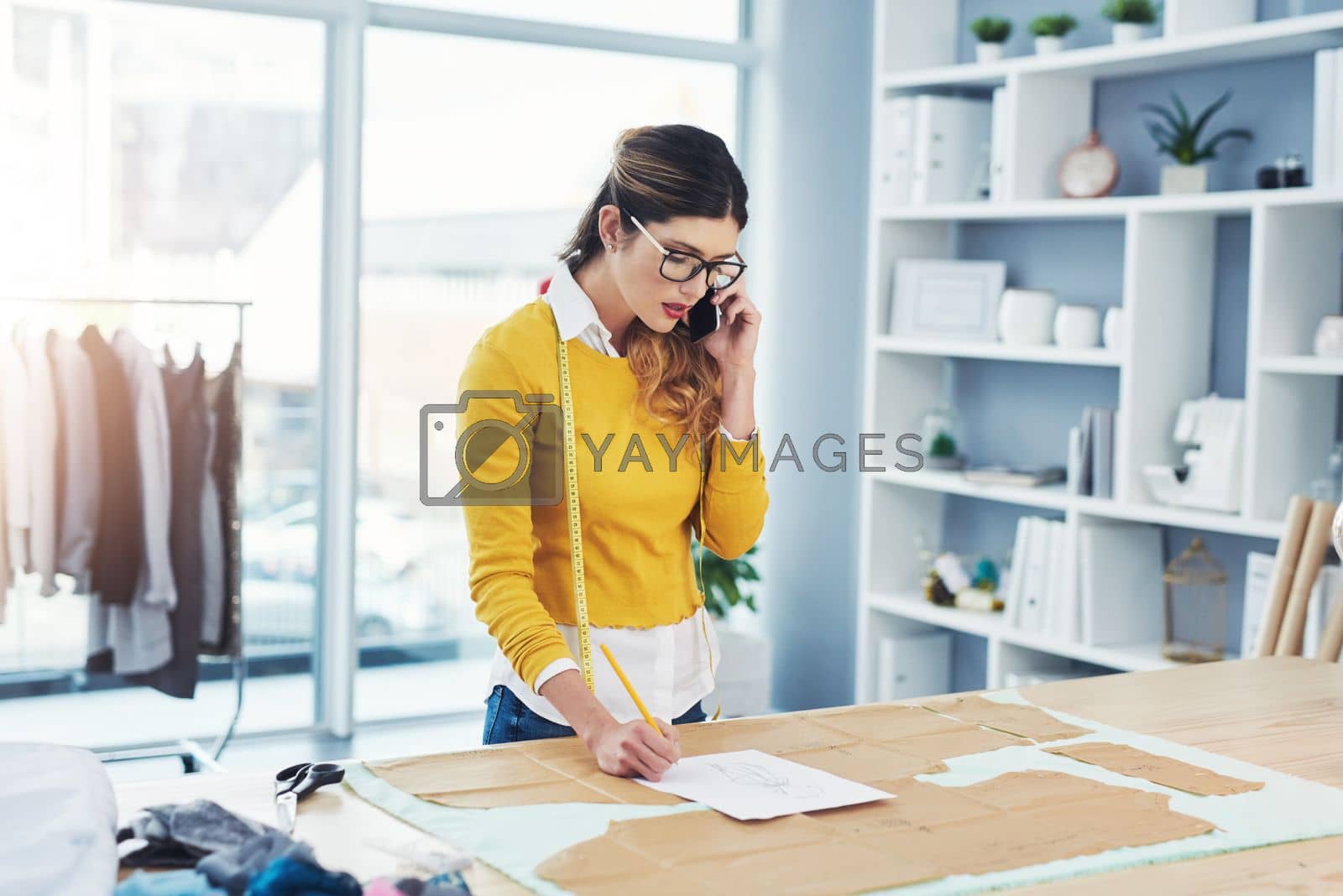 Royalty free image of Lets talk fashion. an attractive young fashion designer in her workshop. by YuriArcurs