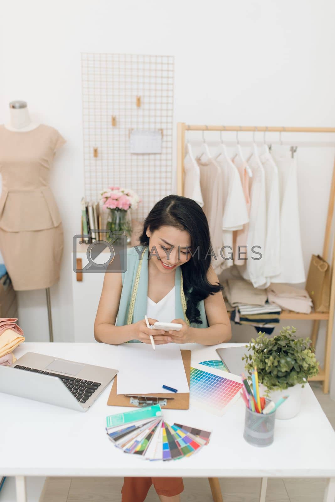 Royalty free image of Portrait of a young Asian fashion designer working on her atelier by makidotvn