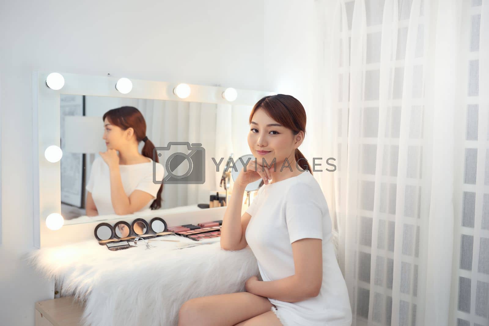 Royalty free image of Happy young Asian woman sitting behind dressing table by makidotvn