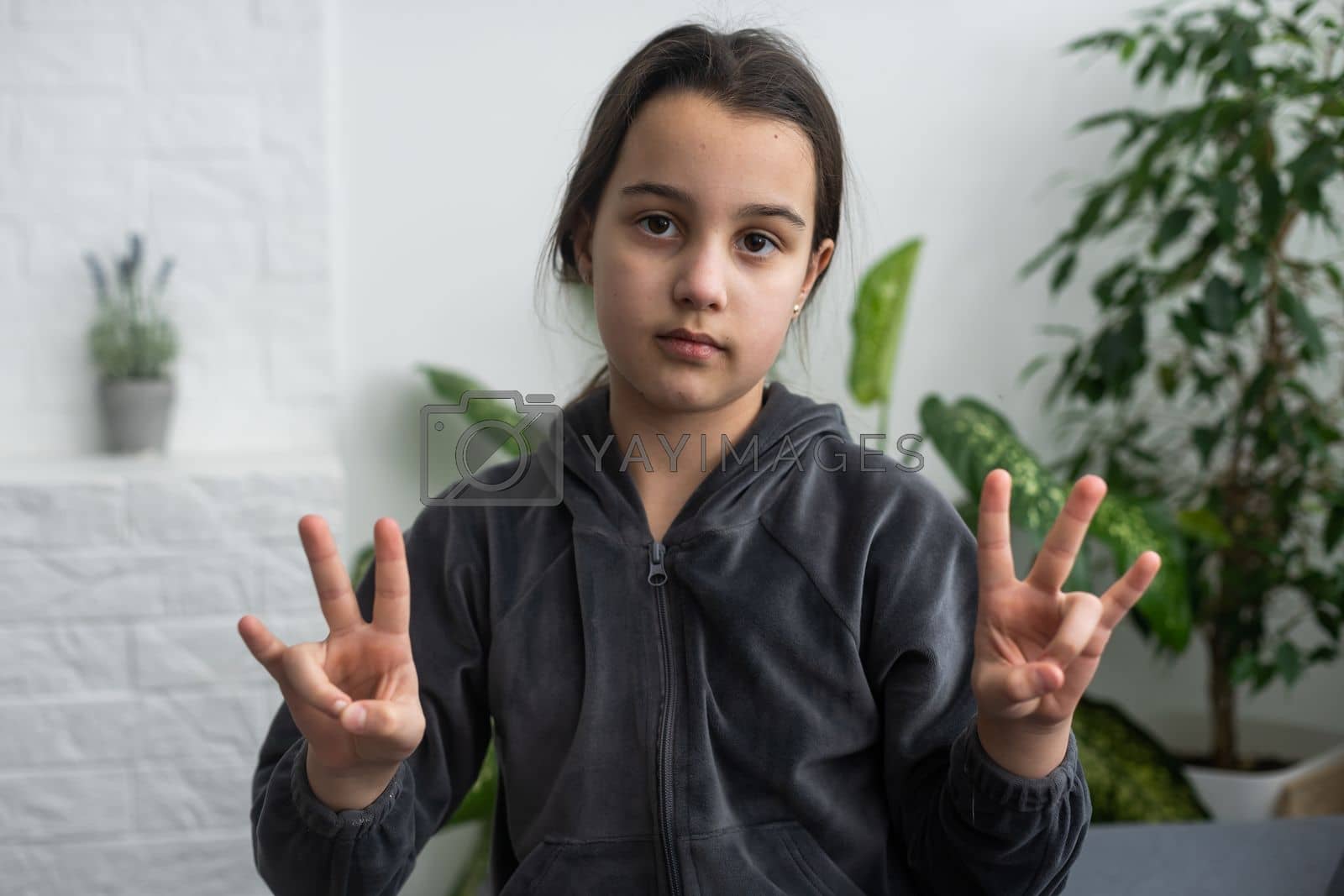 Royalty free image of Cute deaf mute girl using sign language on light background by Andelov13