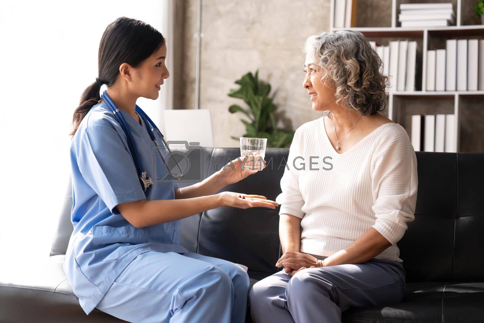 Royalty free image of Healthcare worker or nurse caregiver giving pills, showing a prescription drug to senior woman. Elderly healthcare concept by nateemee