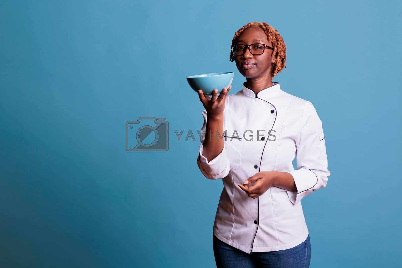 Royalty free image of African american cook showing blue bowl by DCStudio