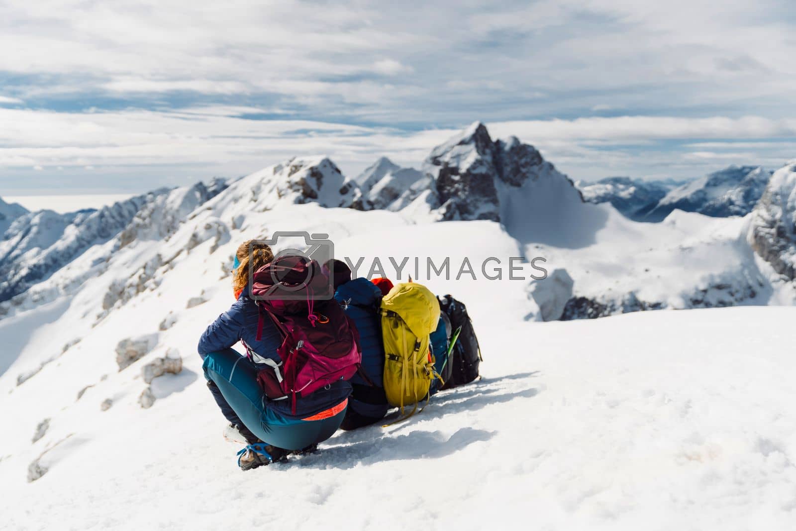 Royalty free image of Back view of hiking couple sitting in the snow enjoying the view of winter Alps from high up by VisualProductions