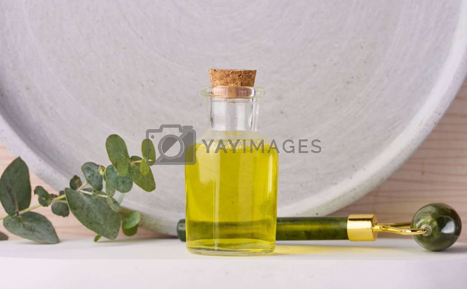 Royalty free image of Transparent glass bottle with yellow oil and eucalyptus branch, cosmetic product by ndanko