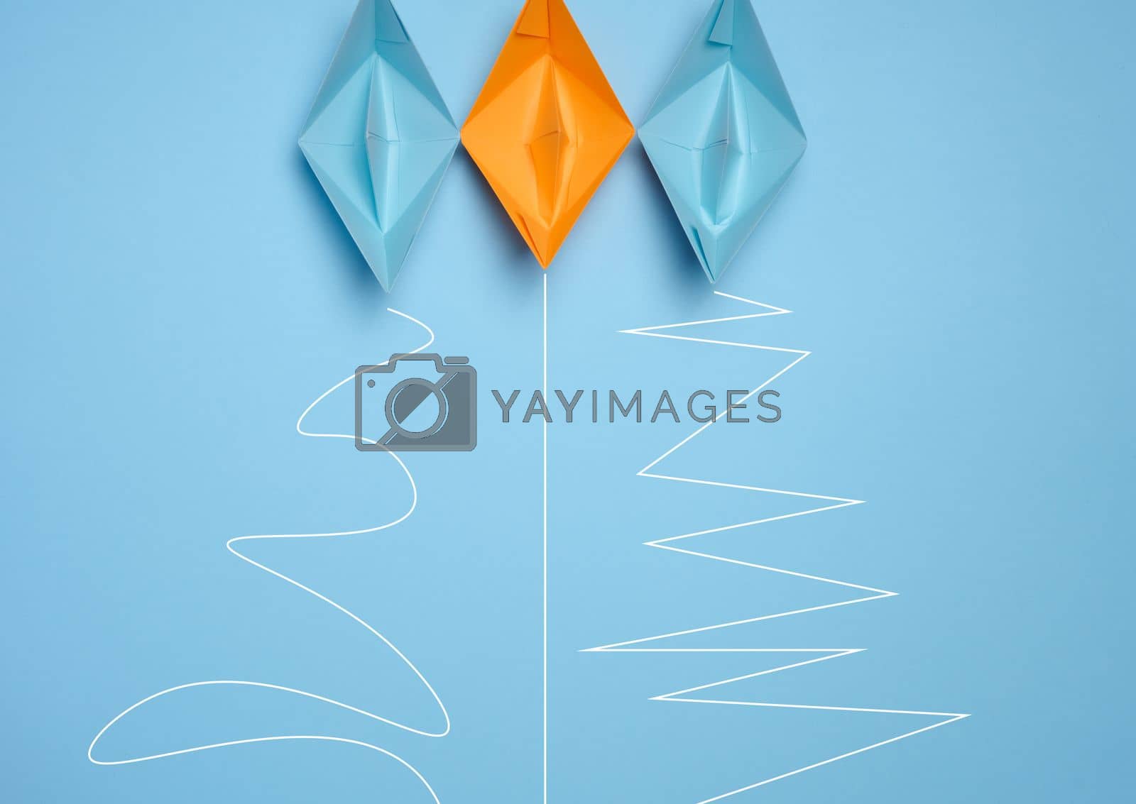 Royalty free image of Three paper boats with different trajectories on a blue background, concept of goal achievement differences, effectiveness by ndanko