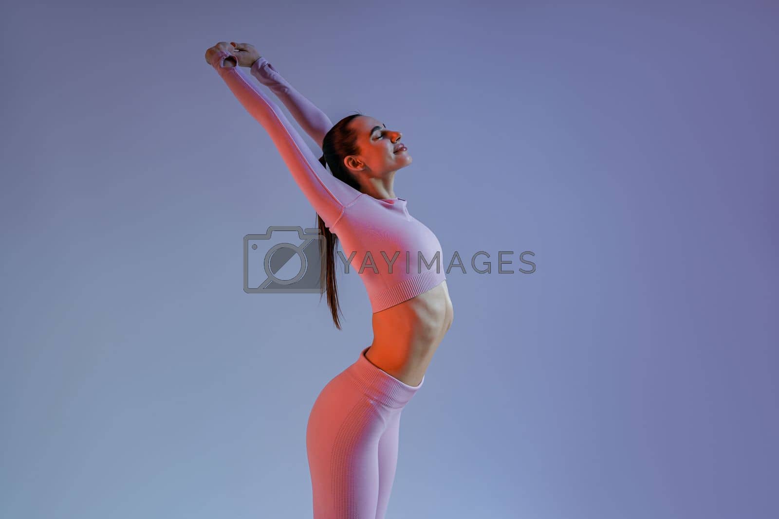 Royalty free image of Close up of woman wearing sportswear doing warm-up before training session on studio background by Yaroslav_astakhov
