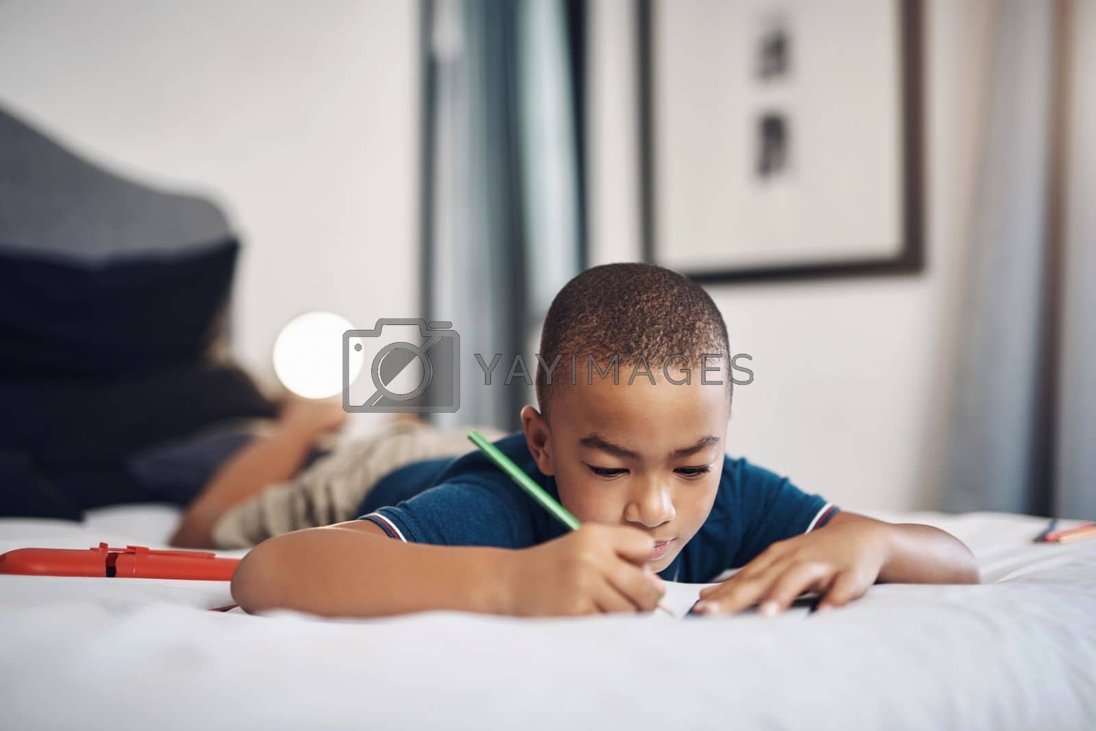 Royalty free image of I like to write letters. a young boy using colouring pencils while drawing at home. by YuriArcurs